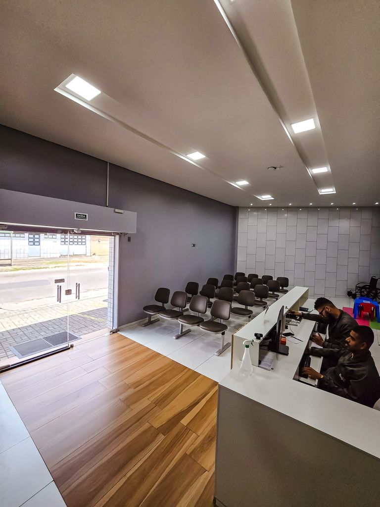 Recepção vista da porta de entrada, com balcão de atendimento e sala de espera ao fundo